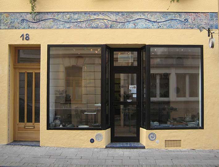 Hausfront der Werkstatt in der Wilhelmstraße 18 mit Schaufenstern und Mosaikband